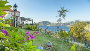 Una propiedad costera con un patio, mobiliario exterior y vistas al mar.