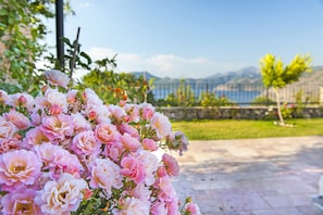 A garden with pink flowers and a stone pathway leading to a view of mountains and a body of water. - Swan Lake Boutique Hotel - Adults Only (Marmaris)