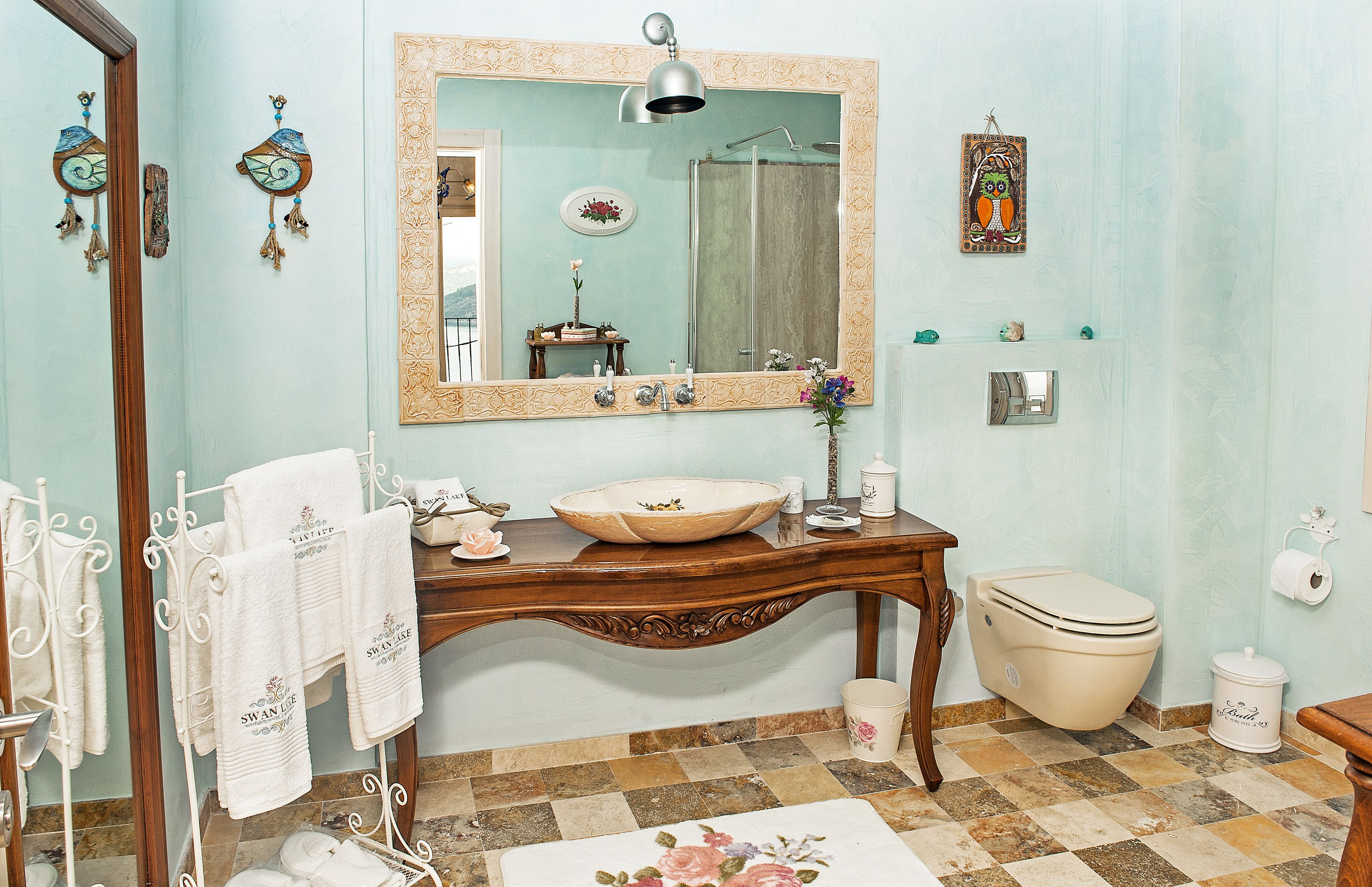 Un baño con un espejo grande, un lavabo, un inodoro y un suelo con diseño.