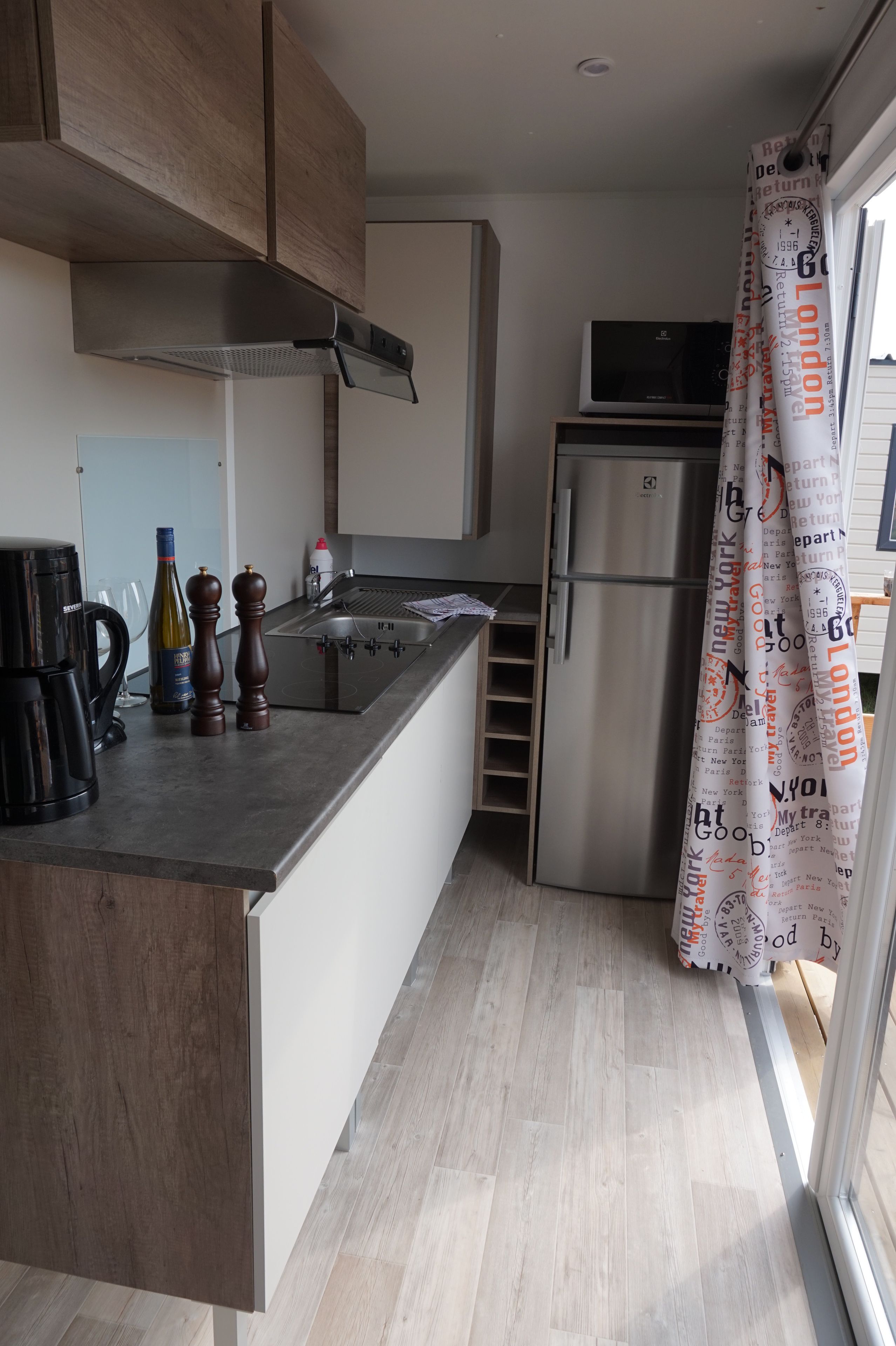 Een moderne keuken met een roestvrijstalen koelkast, een magnetron en een koffiezetapparaat.