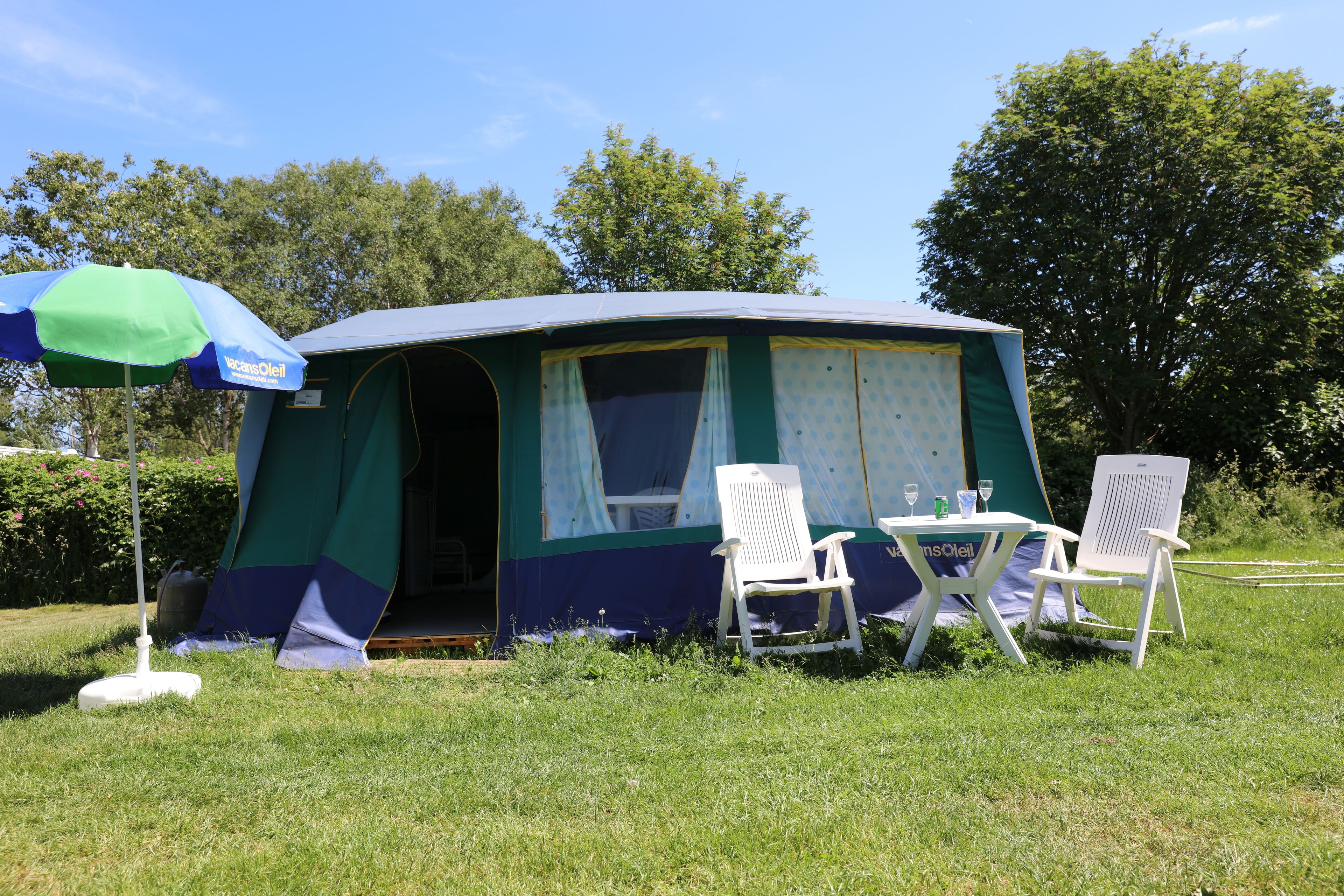 A camping tent with a table and two chairs in a grassy area.