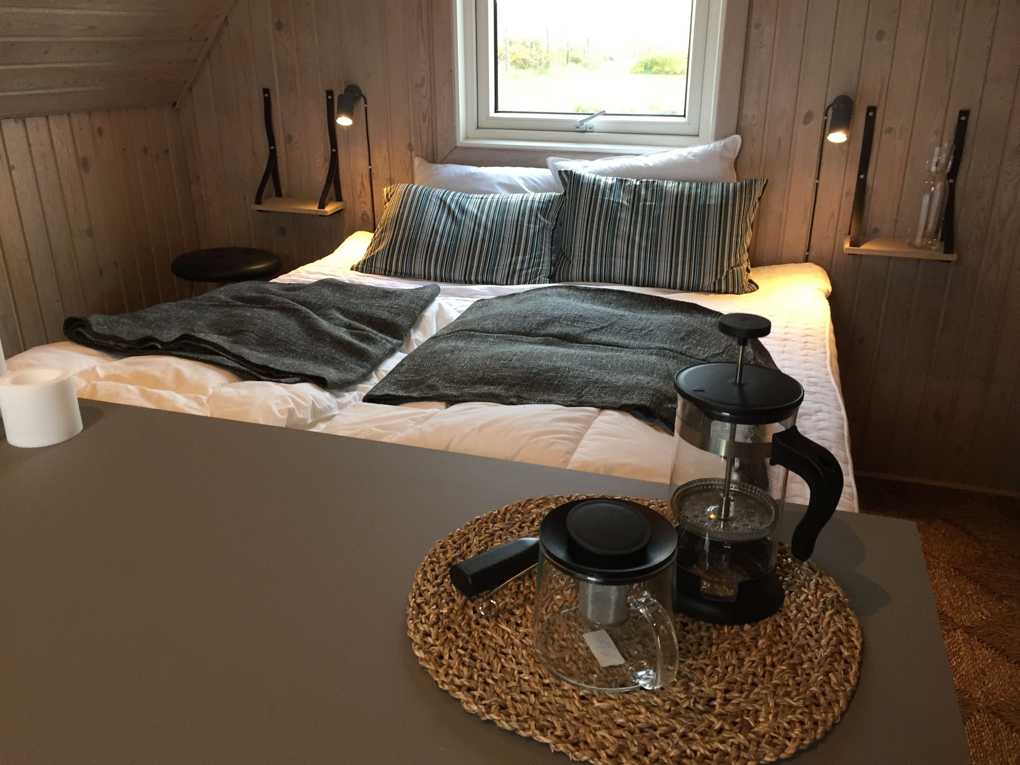 A cozy room with a bed, a coffee maker, and a window with a view of greenery.