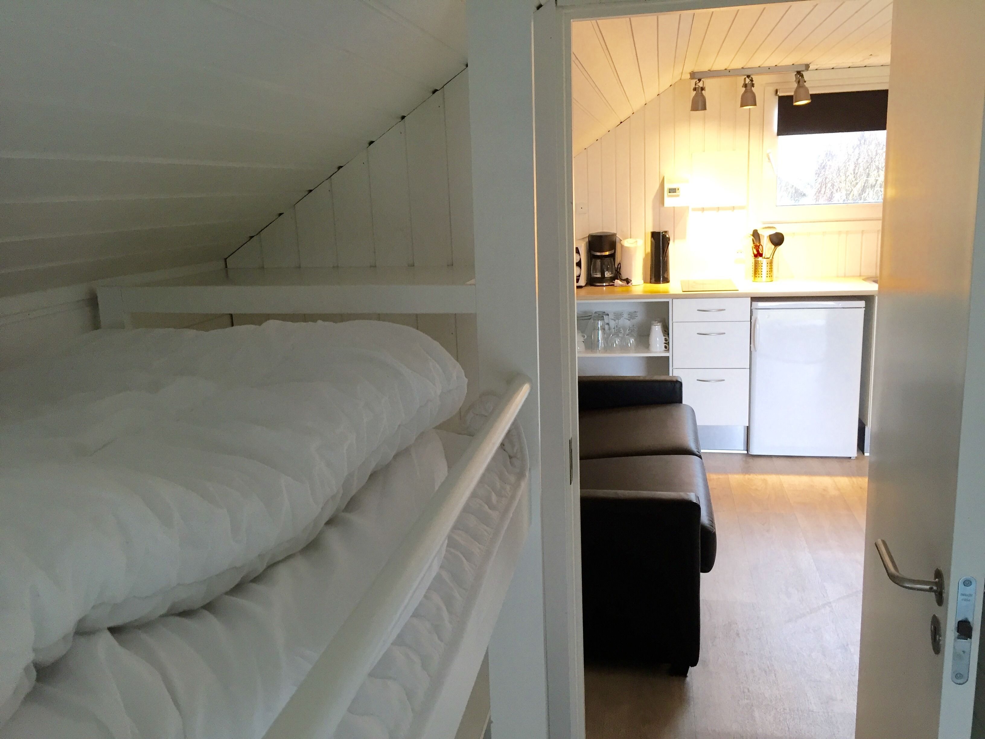 Un dormitorio con una cama litera y una kitchenette en la habitación contigua.