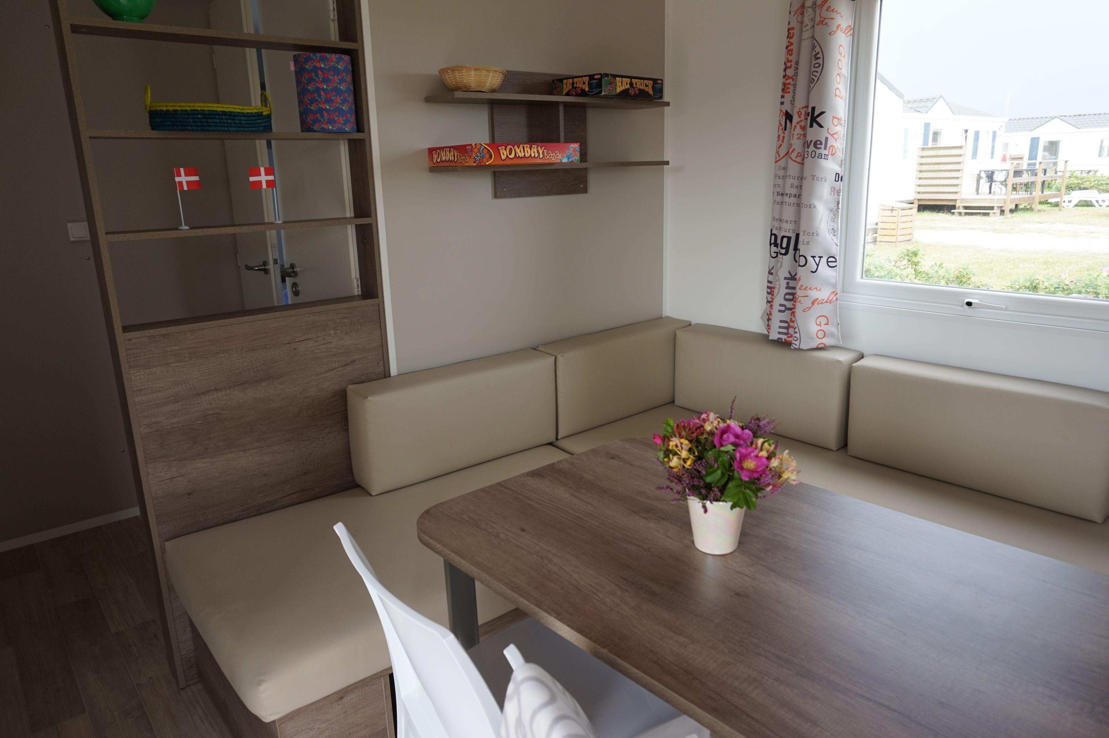Ein gemütliches Zimmer mit einem Holztisch, einer Bank und einem Regal mit verschiedenen Gegenständen, darunter ein Korb und eine Schachtel.
