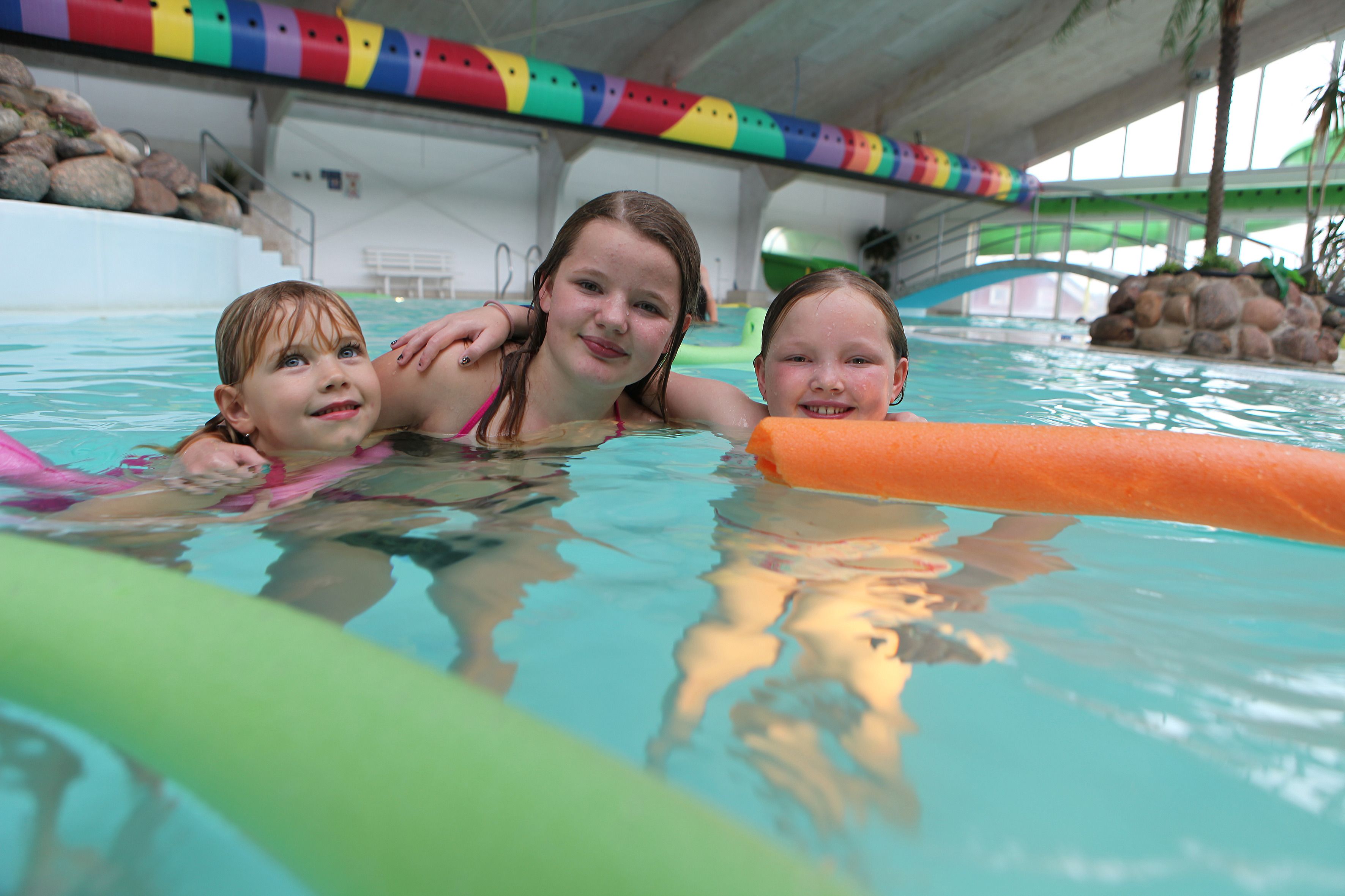 An indoor swimming pool with colorful lane dividers and a rock formation in the background.