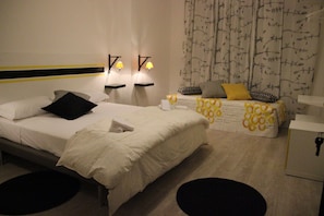 Habitación de hotel con dos camas, un escritorio y un armario. Hay dos mesitas de noche con lámparas.