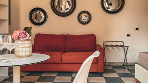 A living room with a red sofa, a white chair, a small table with a vase and glasses, and three wall-mounted mirrors. - Chambres du Monde (Cagliari)