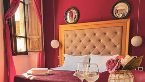 A bedroom with a wooden bed, a bedside table with a vase and glasses, and a window with curtains. - Chambres du Monde (Cagliari)