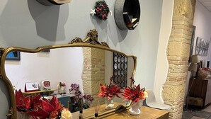 A wooden console table with a large mirror, decorative vases, and a wall-mounted shelf with books. - Chambres du Monde (Cagliari)