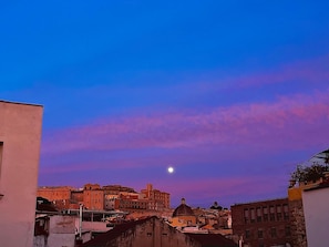 A cityscape at dusk with a visible moon.