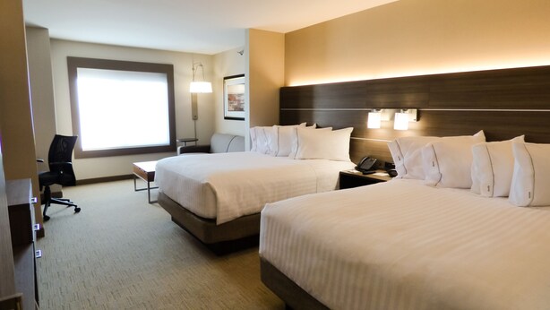 A hotel room with two beds, a desk, a chair, a lamp, and a large window. - Holiday Inn Express & Suites Plymouth - Ann Arbor Area by IHG (Plymouth)
