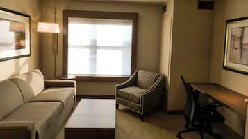 Une chambre d’hôtel équipée d’un canapé, d’un fauteuil, d’un bureau et d’une lampe.
