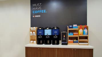 Una estación de café con varios dispensadores, un letrero en la pared y una variedad de productos de café y té.
