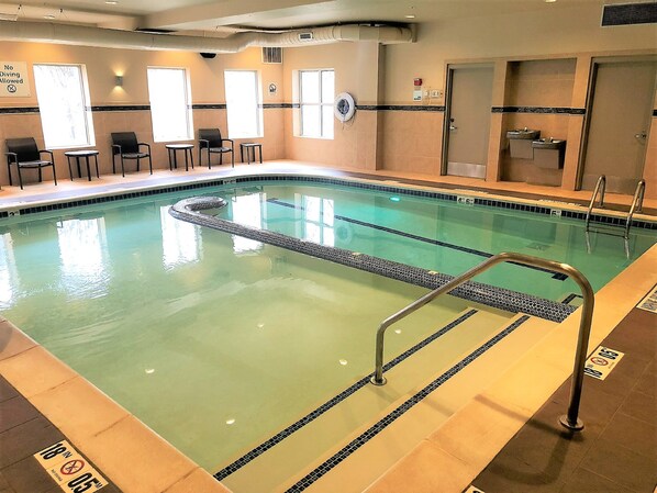 Una piscina interior con agua cristalina, un cartel de zona de buceo y un cartel que indica que está prohibido bucear.
