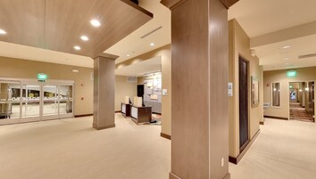 Un vestíbulo de hotel con un mostrador de recepción, un letrero de salida y una puerta de entrada de vidrio.