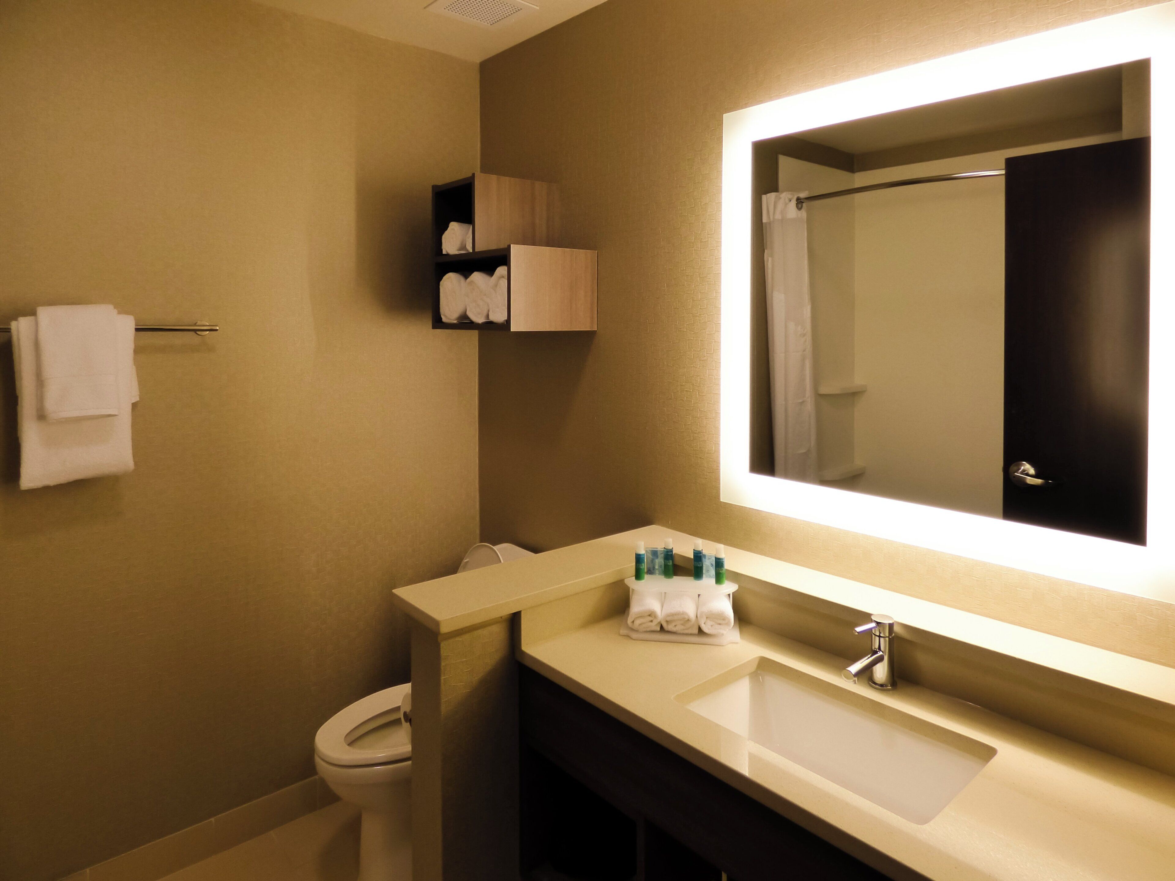 A bathroom with a toilet, sink, and mirror.
