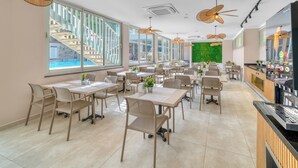 A spacious restaurant with high ceilings, large windows, and a green wall. Tables and chairs are arranged for dining. - Park Hotel (Alanya)