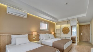 A hotel room with two beds, a wall-mounted air conditioner, a decorative wall piece, and a wooden door. - Park Hotel (Alanya)