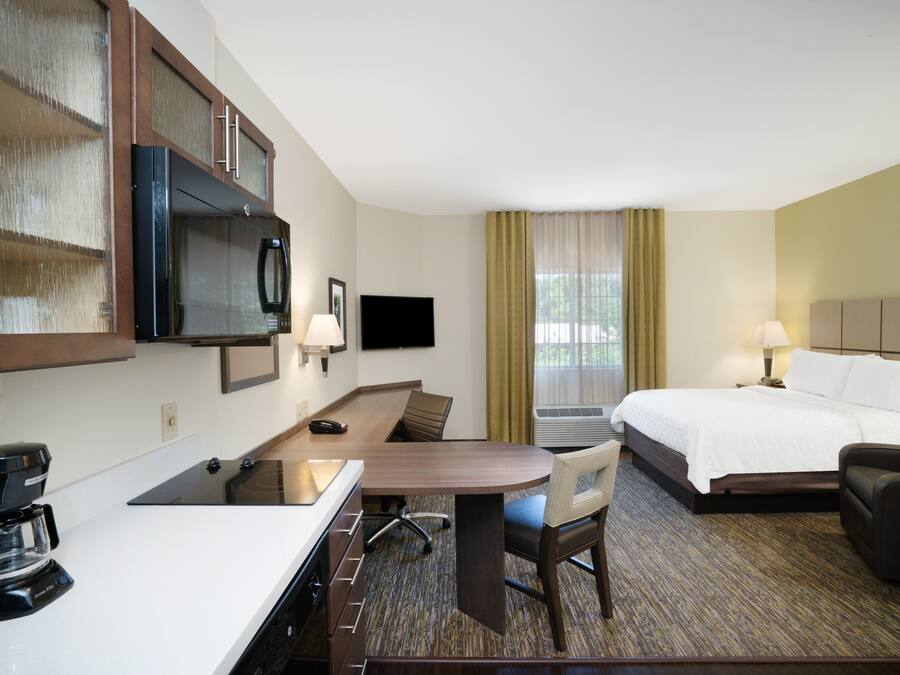 Ein Hotelzimmer mit Bett, Schreibtisch, Sessel, Fernseher, Kaffeemaschine und Klimaanlage.