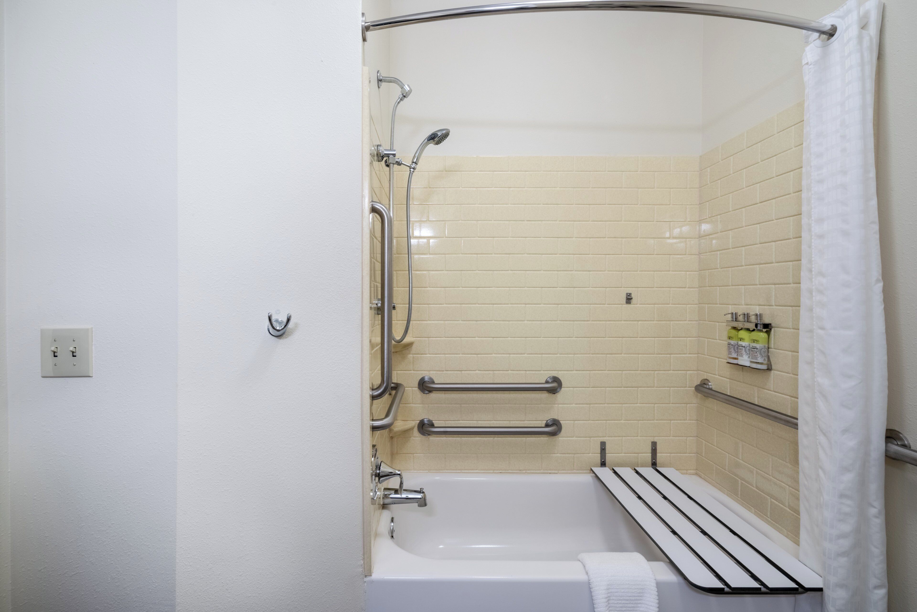 Een badkamer met een bad, een douche en een handgreep.