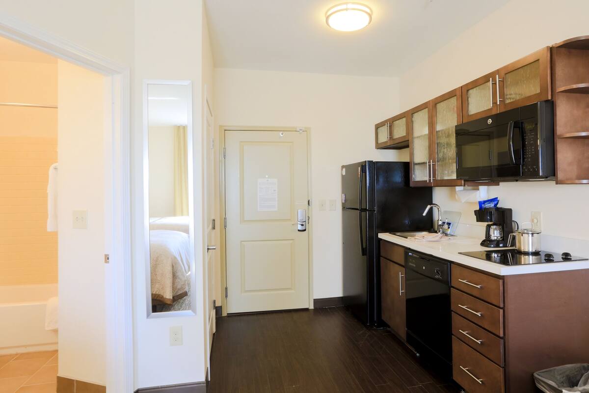 A compact kitchen with a refrigerator, microwave, and a coffee maker on the counter.