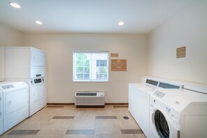A laundry room with a washer and dryer, a vent, and a window.
