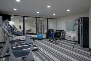 A gym with exercise equipment, a mirrored wall, and a window with blinds. - Candlewood Suites Auburn by IHG (Auburn)