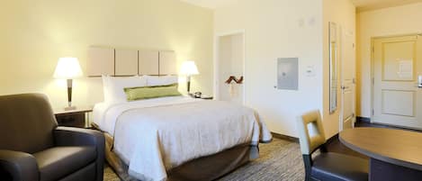 Une chambre d’hôtel avec un lit, deux lampes de chevet, une chaise, un bureau et une porte.