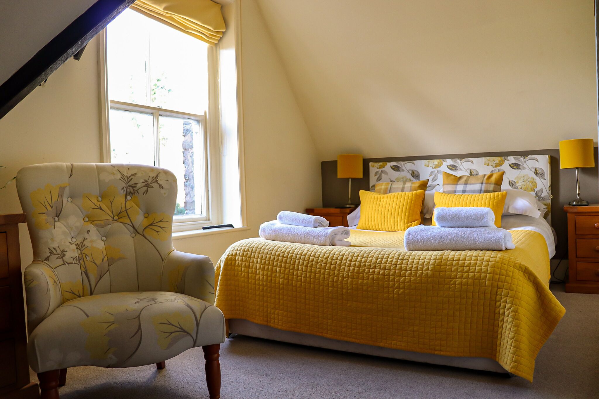 A bedroom with a bed, a chair, and a window.