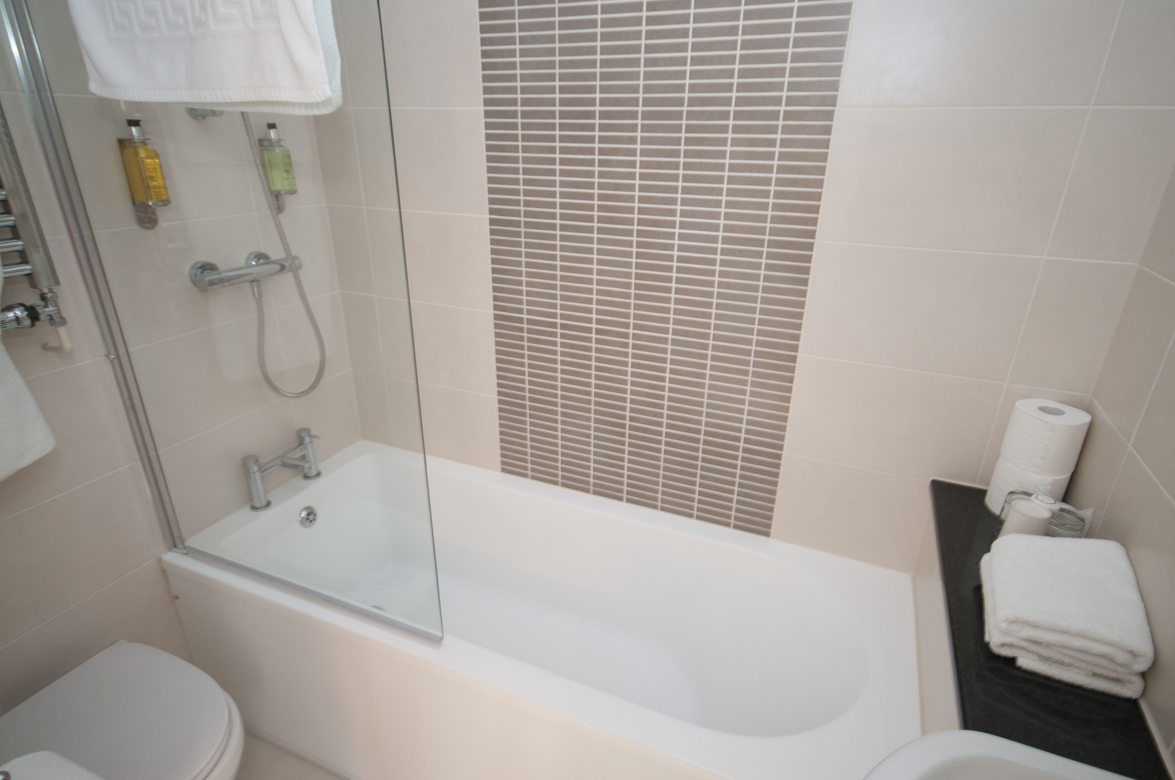 Un baño moderno con bañera, inodoro y zona de ducha.