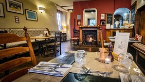 A restaurant interior with a fireplace, wooden furniture, and a menu board. - The Castle Hotel (Bishops Castle)