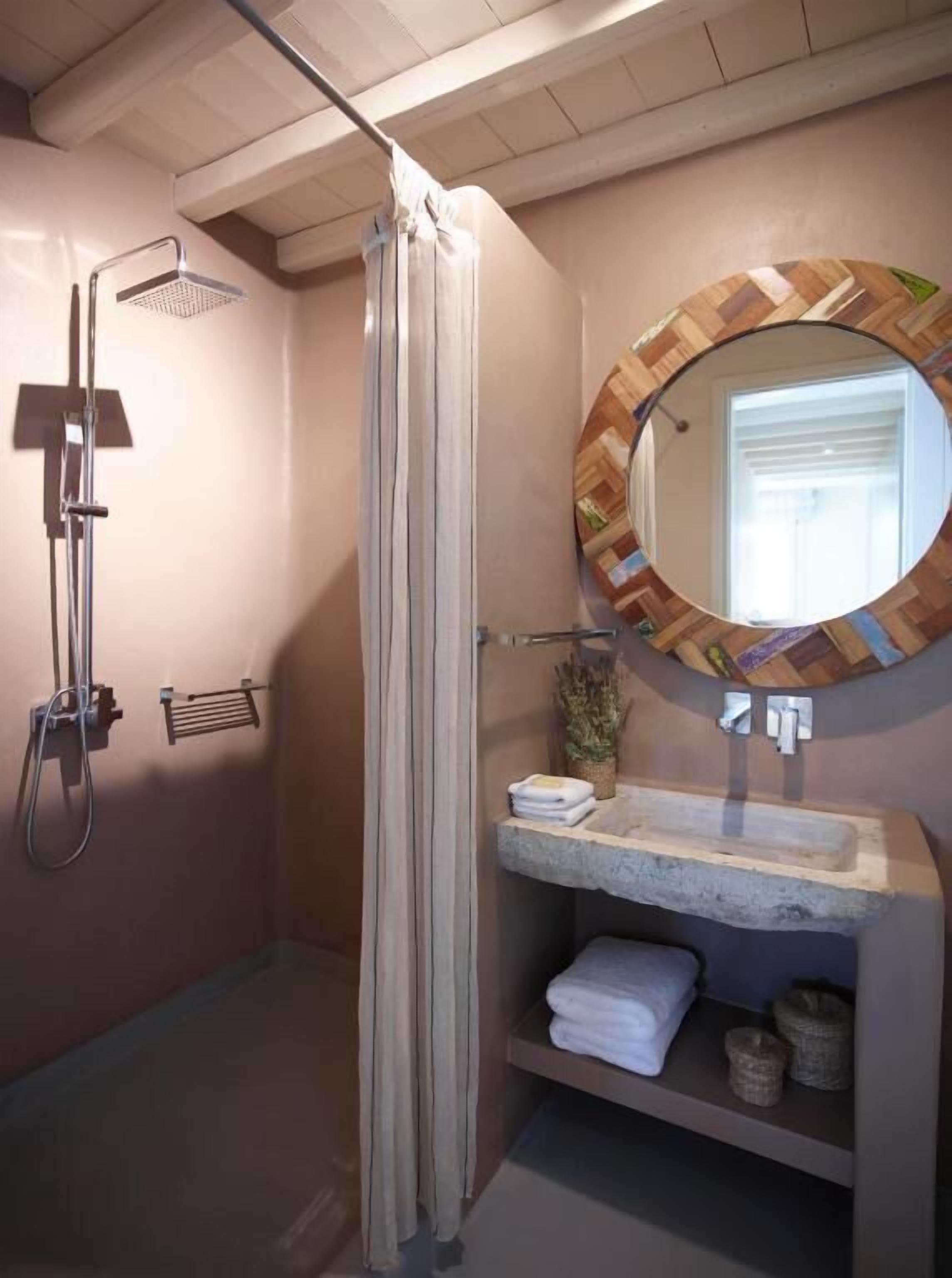 A bathroom with a shower, a mirror, and a shelf with towels.