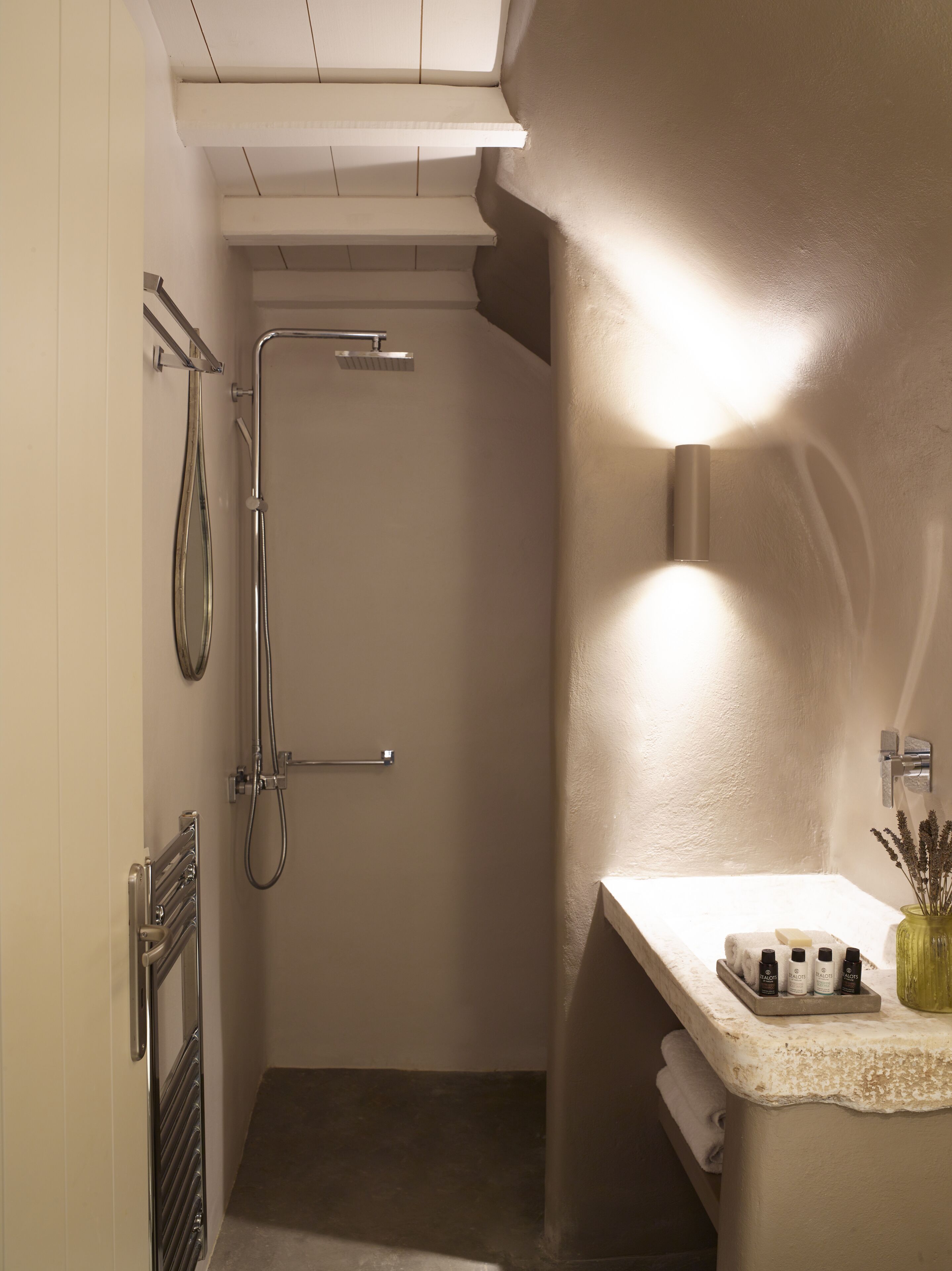 A modern bathroom with a shower, a vanity with toiletries, and a towel rack.
