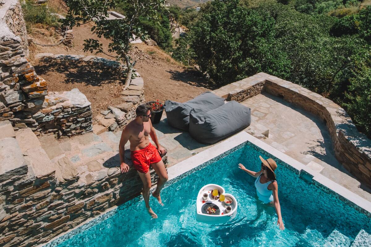 A pool with a stone edge and a view of the sea.