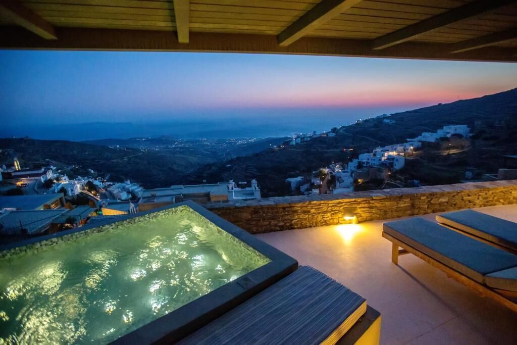 A hot tub with a view of a hillside village at dusk.