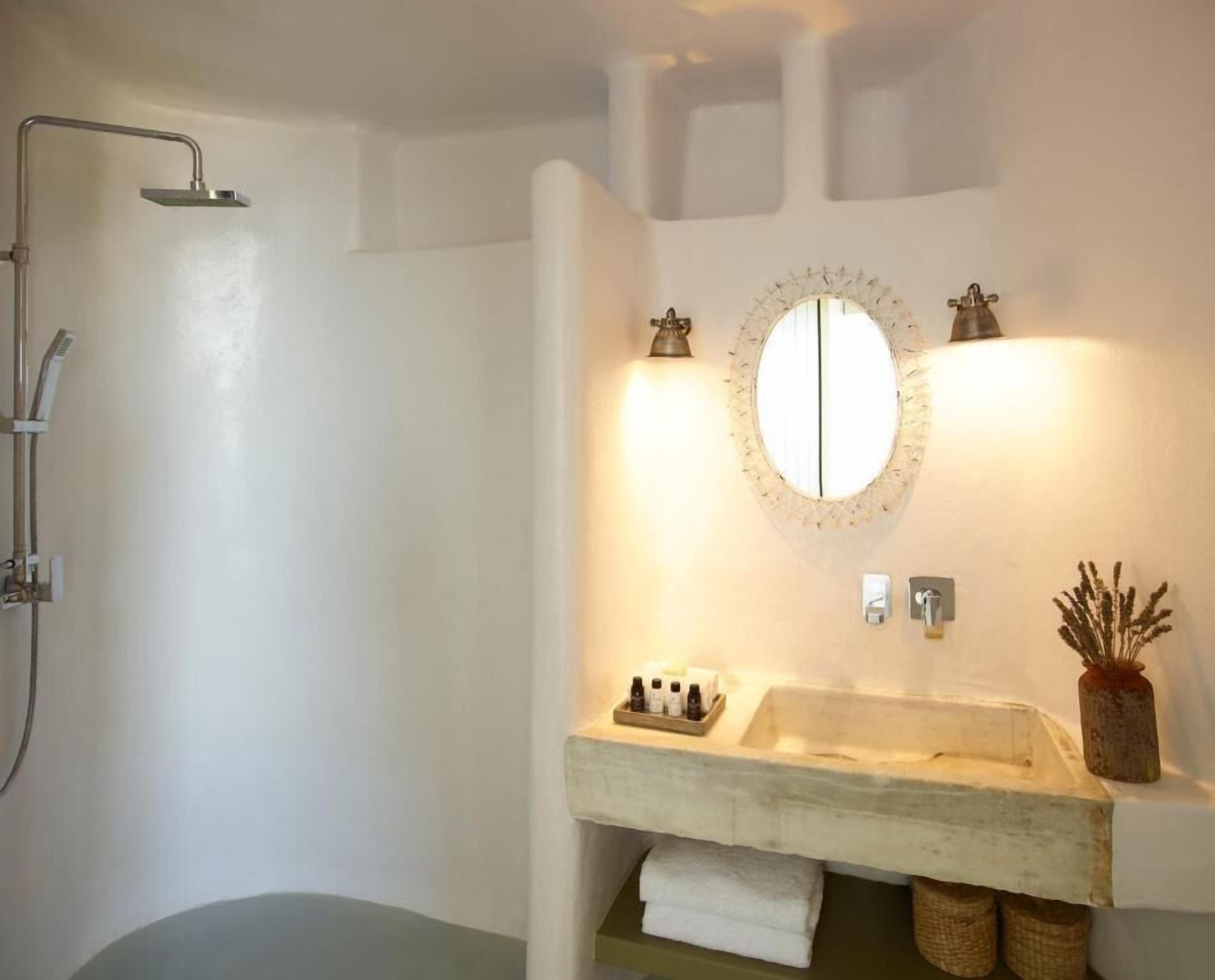 Un baño con ducha, lavamanos, espejo y toallero.