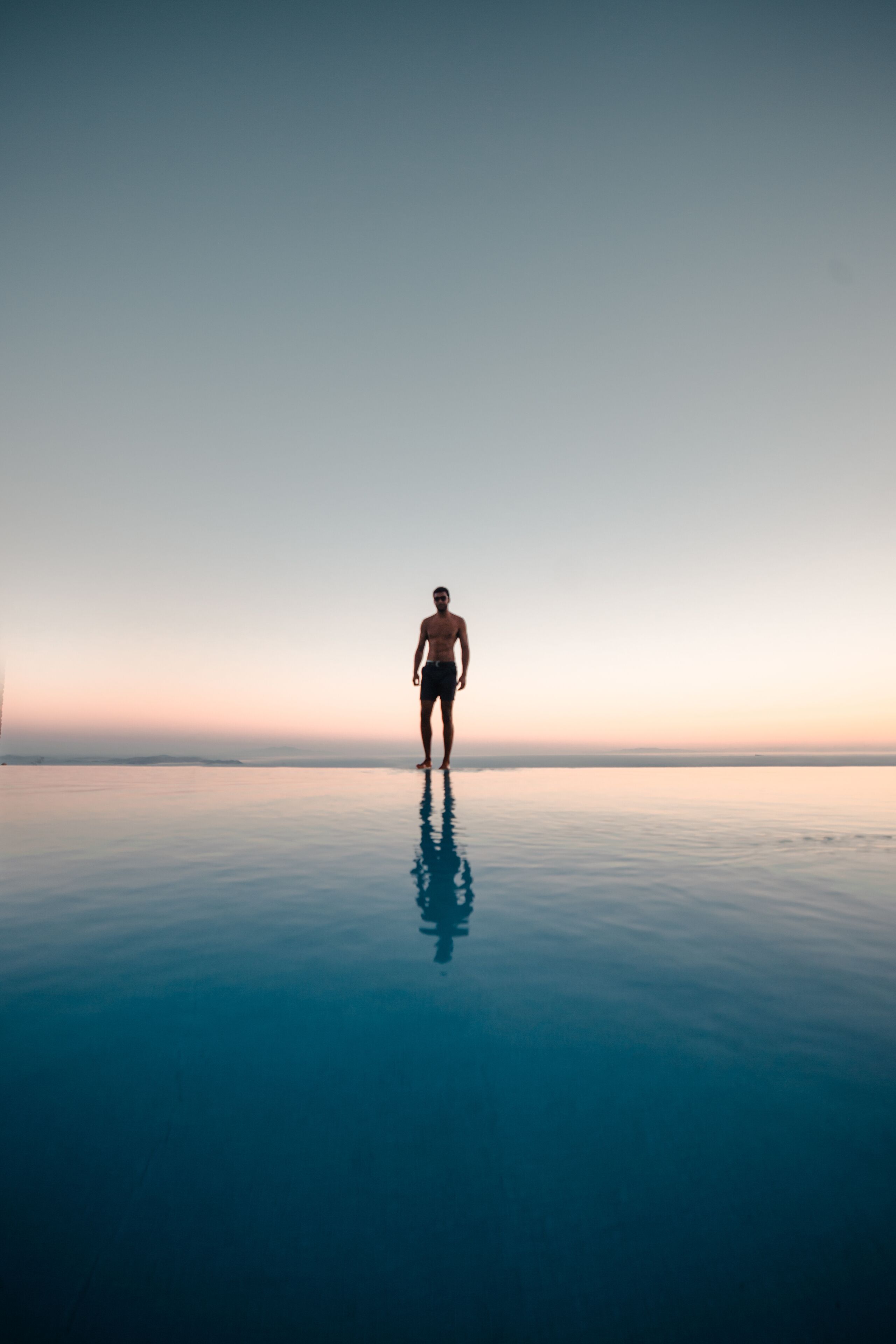 A person standing on a reflective surface with a clear sky in the background.