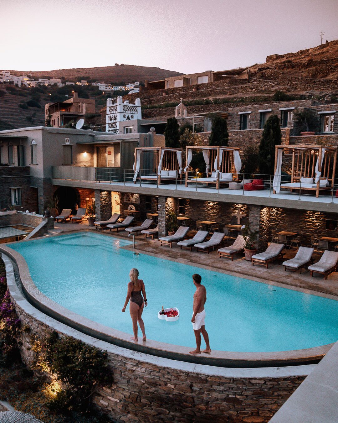 A poolside area with lounge chairs and a couple standing by the pool.