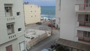 A street view with buildings, a parked car, and a view of the sea. - Despina Hotel (Hersonissos)