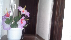 A potted plant with flowers on a wooden table in a hallway. - Despina Hotel (Hersonissos)