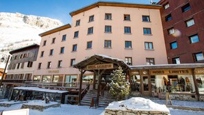 Un hotel de varios pisos, con entrada cubierta y terreno cubierto de nieve.