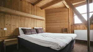 Un dormitorio de cabaña de madera con una cama, una mesita de noche y una ventana.