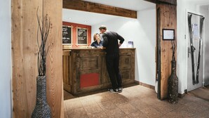Un mostrador de recepción con encimera de madera, un menú en una pizarra y una puerta de madera decorada con esquíes.