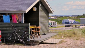 Une petite cabane en bois avec une véranda, un vélo et une table avec des chaises.