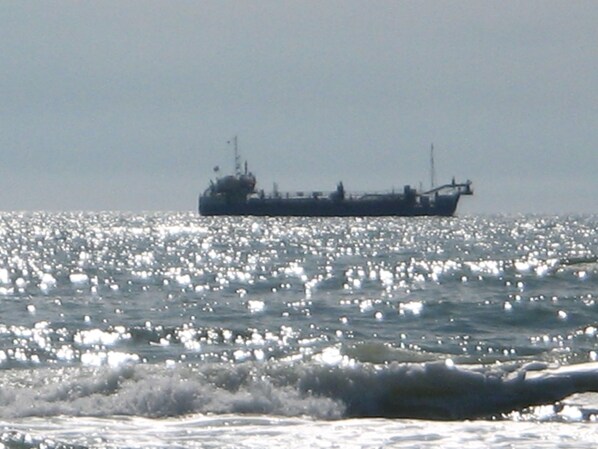 Un gran carguero en un mar tranquilo con el sol reflejándose en el agua.