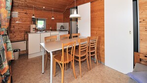 Une cuisine de taille réduite avec des murs en bois, une table à manger avec des chaises et un réfrigérateur.