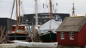 Un quai avec plusieurs bateaux, un bâtiment rouge et une grande enseigne en arrière-plan.