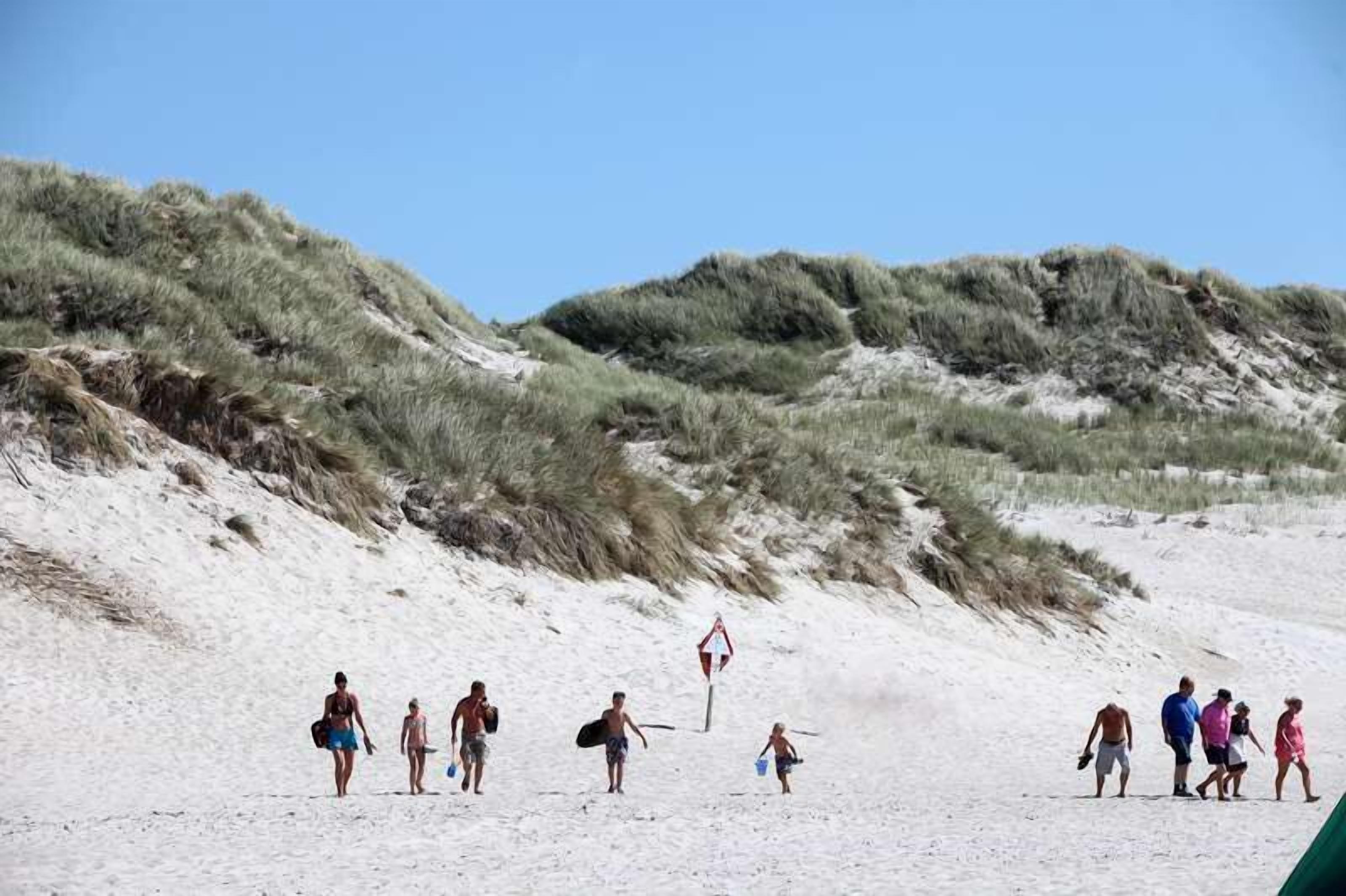 A sandy beach with dunes and a lifeguard sign.