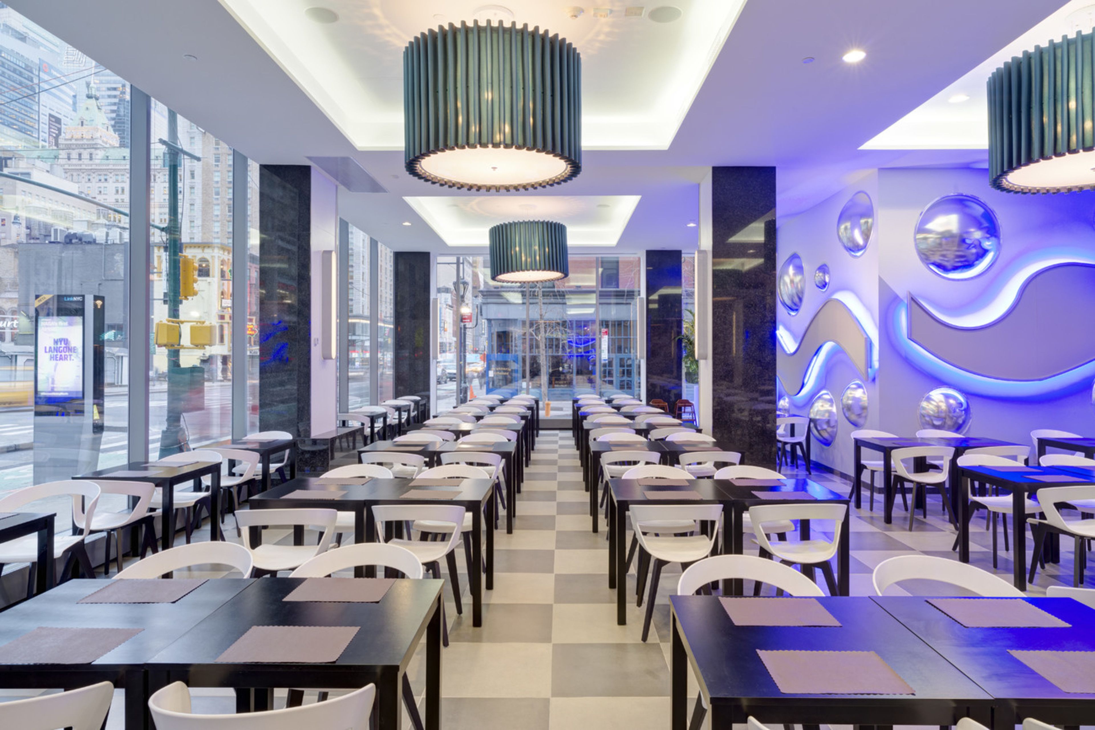 Un restaurante moderno con suelo a cuadros, varias mesas y sillas, y elementos decorativos en las paredes.