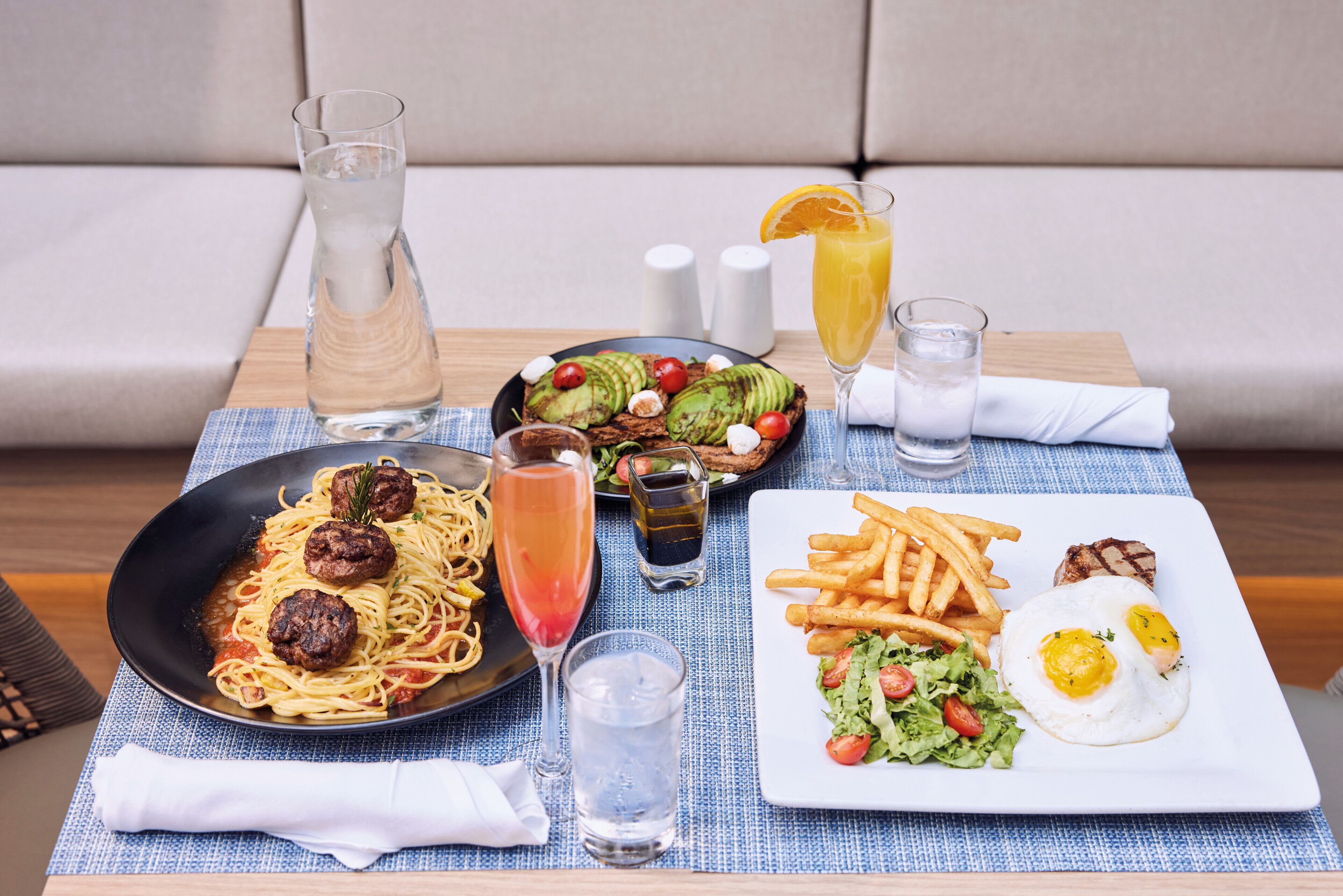 Une table proposant une variété d’aliments pour le petit-déjeuner, notamment des pâtes, des œufs et une boisson.